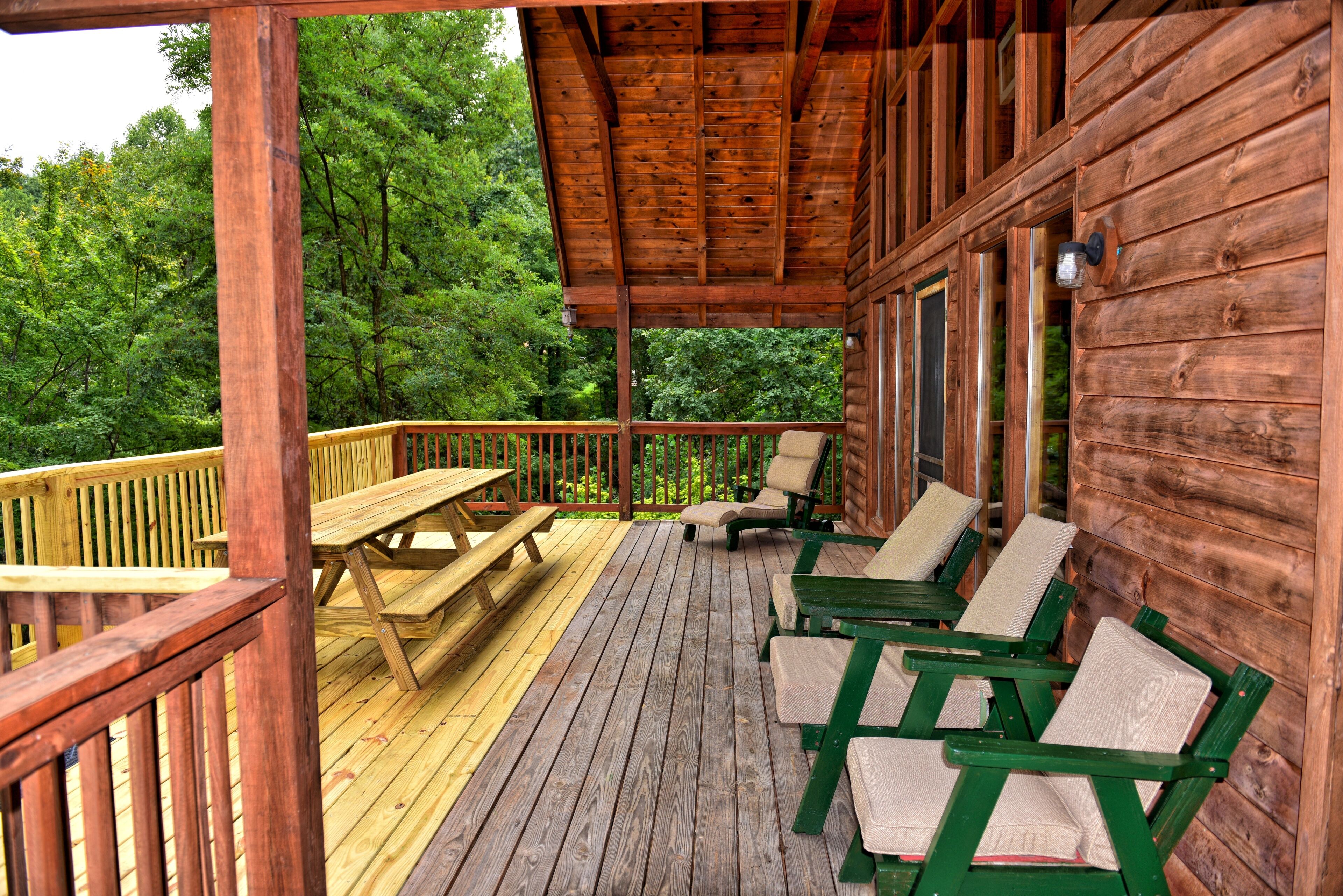 Eine Holzdielen-Terrasse mit Picknicktischen und -stühlen, umgeben von einer Holzhütte mit einer Veranda.