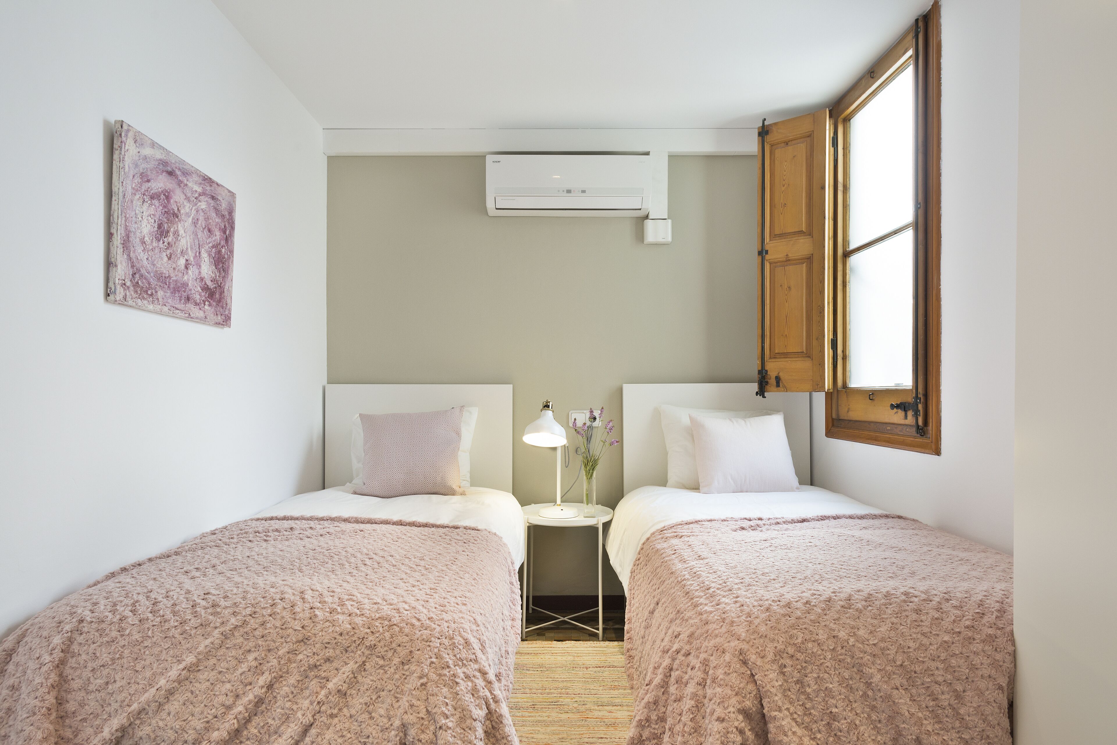 Un dormitorio con dos camas, una mesita de noche con una lámpara y un equipo de aire acondicionado.