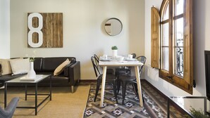 A modern living room with a sofa, a coffee table, a dining table with chairs, a large mirror, and a decorative number eight.