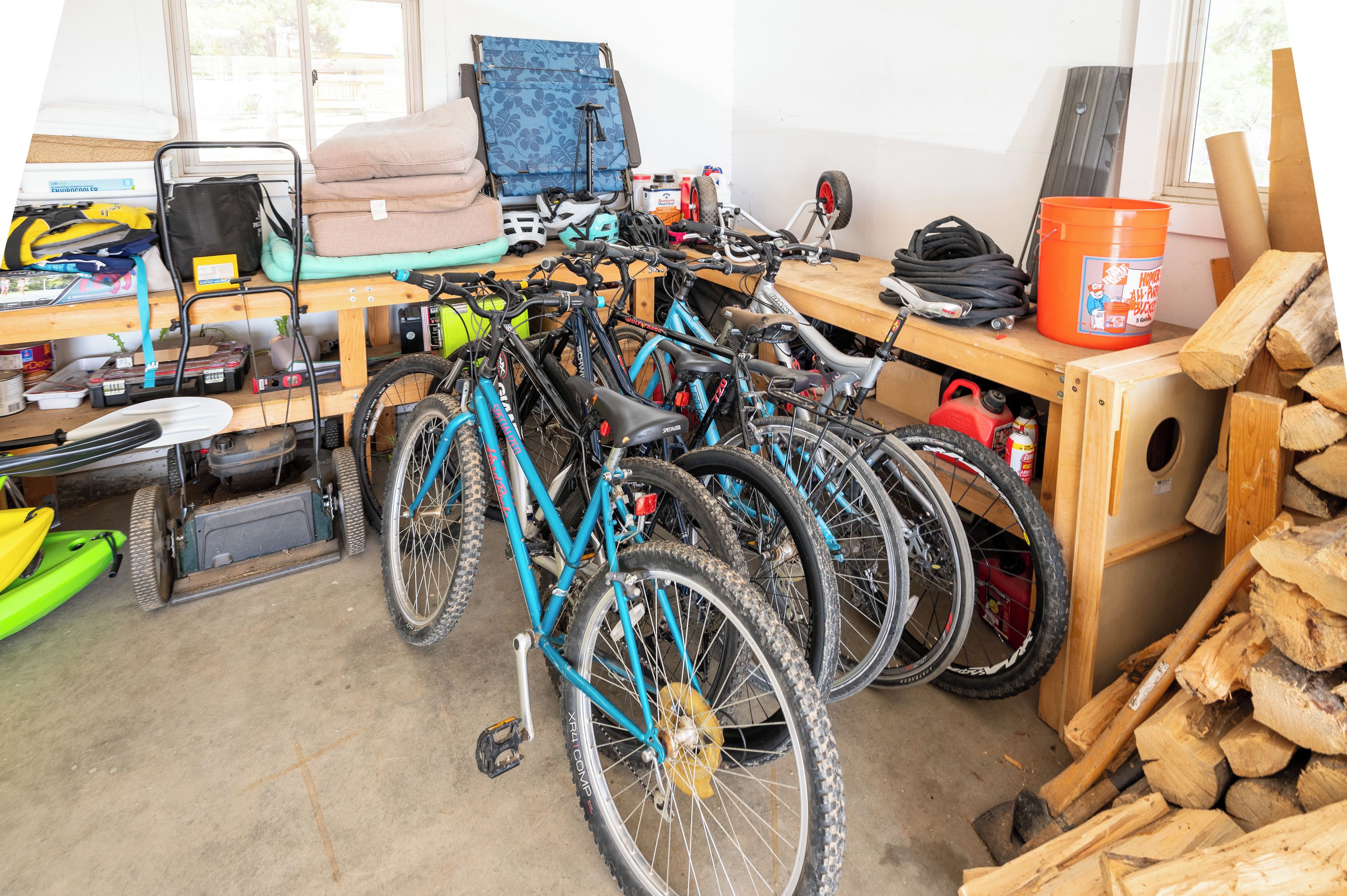 Garage with multiple bikes, helmets, and firewood for wood burning stove and fire pit