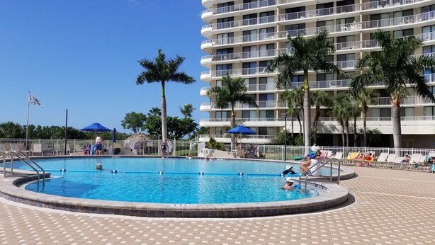Ein Poolbereich mit einem runden Pool, Liegestühlen und Sonnenschirmen.