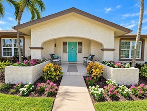 A two-story house with a front porch, a teal door, and a pathway leading to the entrance. - 5-Min Walk to Beach! Private Heated Pool & 5BR Home (Marco Island)