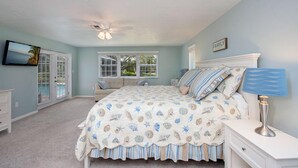 A bedroom with a bed, a nightstand, a ceiling fan, a TV, and a window. - 5-Min Walk to Beach! Private Heated Pool & 5BR Home (Marco Island)