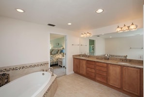 A bathroom with a large bathtub, wooden cabinets, a sink, and a mirror. - 5-Min Walk to Beach! Private Heated Pool & 5BR Home (Marco Island)