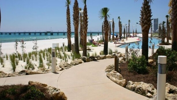 A beach resort with a pool, palm trees, and a pier in the background. - {L@@K}  Beach FRONT, Home @ the Beach w/Beach Chair Service {L@@K} (Panama City Beach)