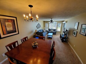 A dining area with a wooden table and chairs, a chandelier, and a framed picture on the wall.