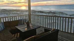 Una terraza con vista a la playa y al océano al atardecer.