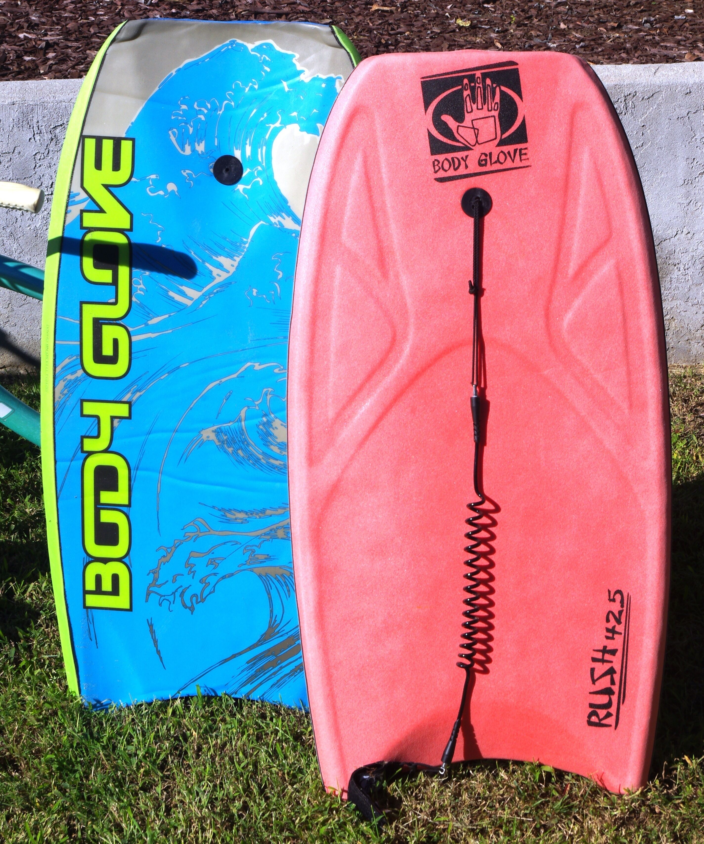 Two body gloves, one blue and one pink, placed on grass.