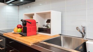 A modern kitchen with a red espresso machine, a sink, and a white cabinet with a Nespresso logo.