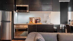 A modern kitchen with dark cabinetry, stainless steel appliances, and a built-in oven.