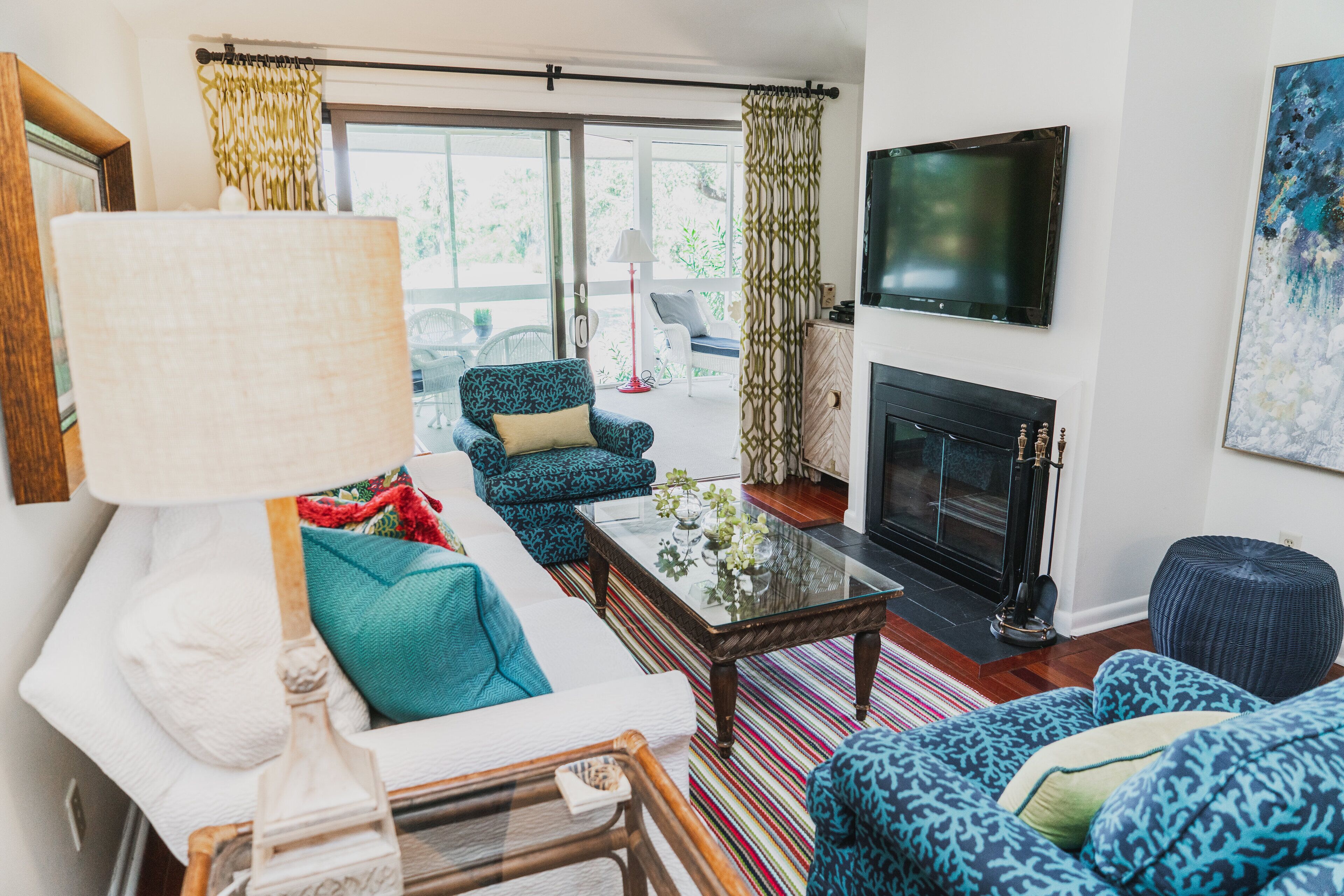 A living room with a sofa, patterned chairs, a coffee table, a TV, and a fireplace.