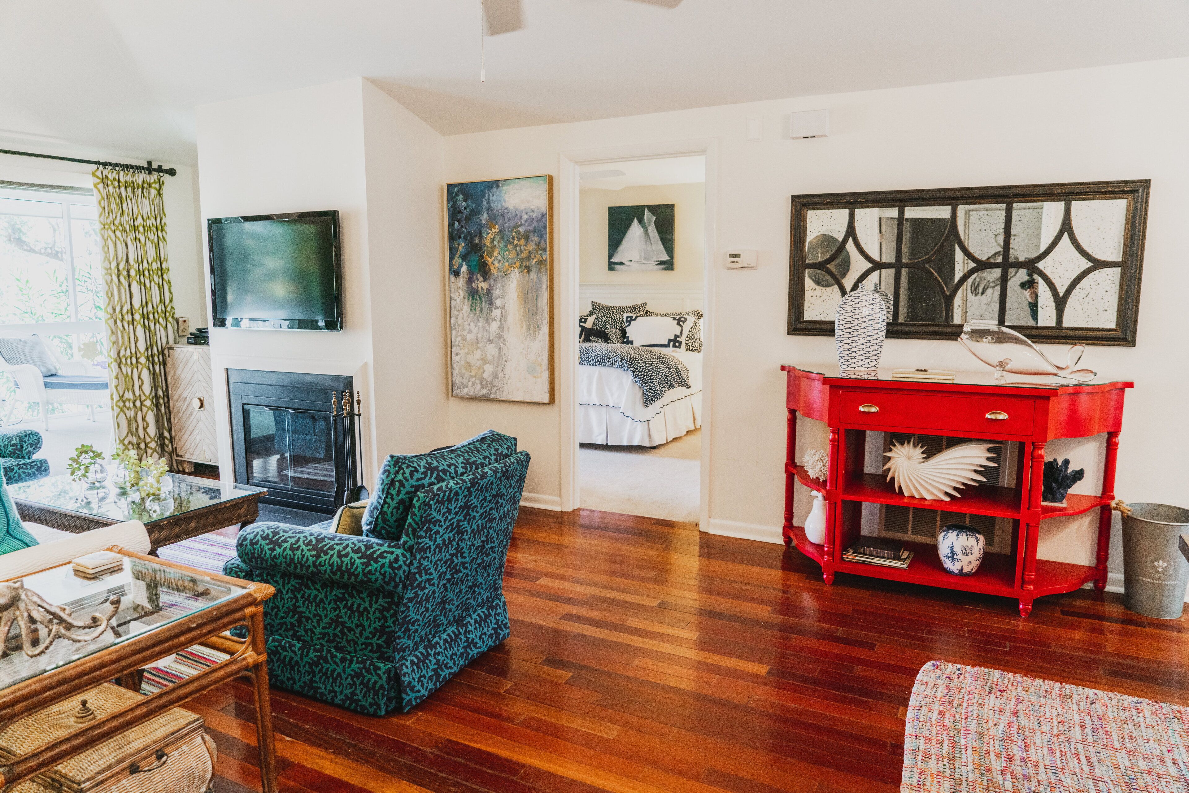 Una sala de estar con chimenea, televisor y un aparador rojo.