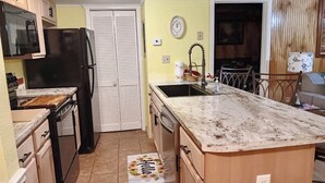 A compact kitchen with a refrigerator, microwave, sink, and wooden cabinets.