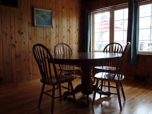Enjoy meals in this cozy dining area with a wooden table and four chairs, surrounded by a beautiful view.
