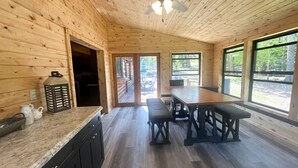 A wooden cabin interior with a kitchen, dining area, and large windows. - A large, newly remodeled 7,000 sq ft cabin, new hot tub, minutes from Deadwood! (Lead)