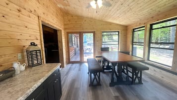 L’intérieur d’un chalet en bois comprend une cuisine, un coin repas et de grandes fenêtres.