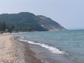 Ein kiesiger Strand mit einem Gazebo und einer Hügelkulisse im Hintergrund.