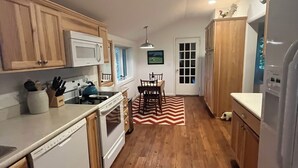 A compact kitchen with wooden cabinets, a microwave, a stove, and a refrigerator.