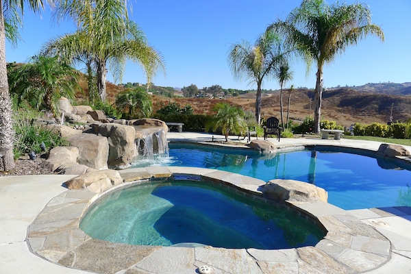 Spa, waterfall and pool with hills and vineyards in distance