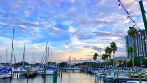 A marina with boats docked, a clear sky, and palm trees.