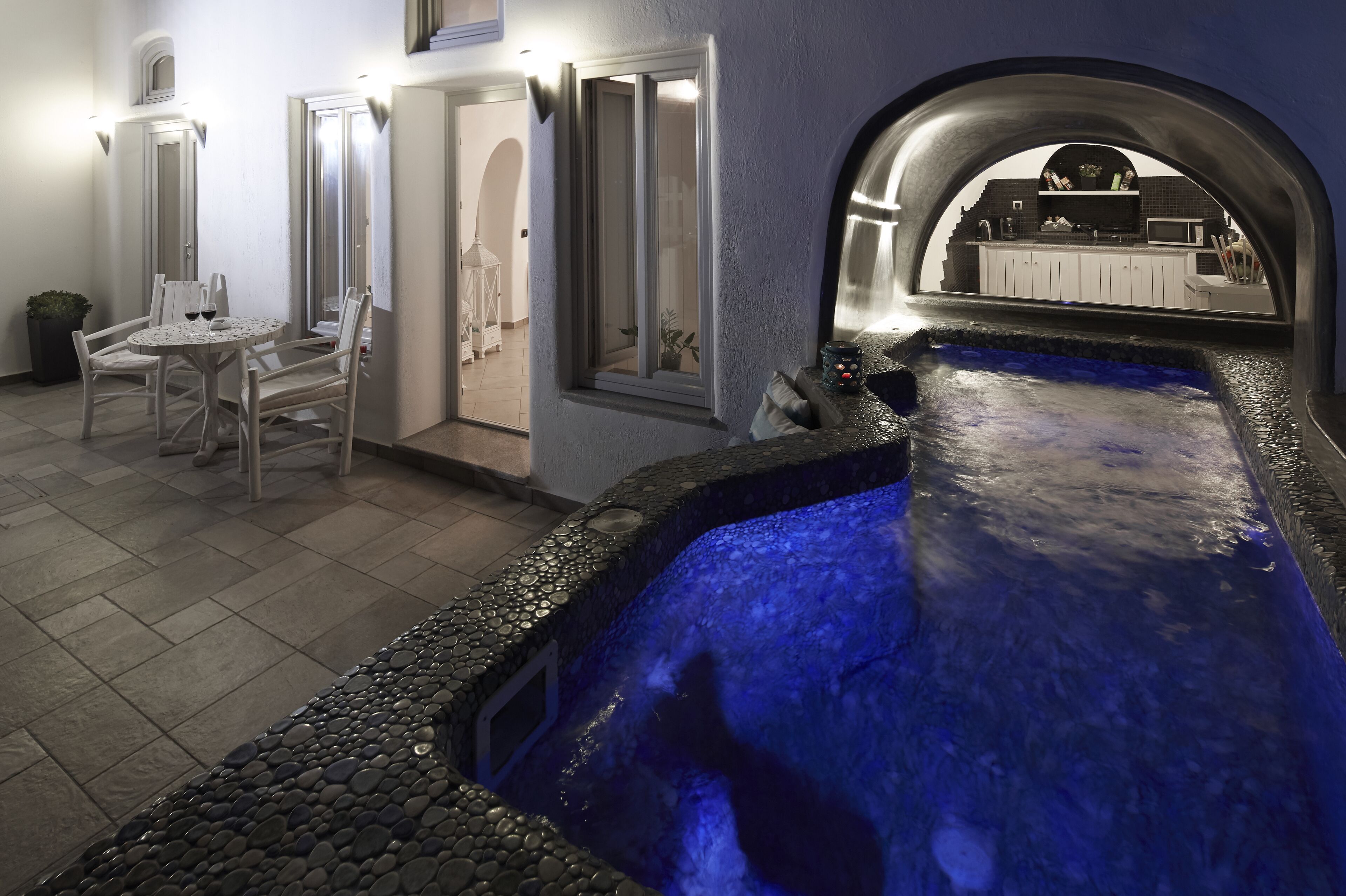 Een wellnessruimte met een jacuzzi, zitplaatsen en uitzicht op de keuken.