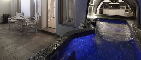 Een wellnessruimte met een jacuzzi, zitplaatsen en uitzicht op de keuken.