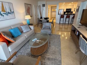 A modern living room with a sofa, coffee table, and a dining area with chairs.