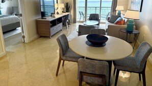 A hotel room with a dining area, a TV, a desk, and a balcony with a view of the sea. - Direct Oceanfront 1,200sf 1BR/2Bth Condo; Full 4star Hotel Service; Walk to All! (Fort Lauderdale)