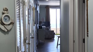 Een gang met een betegelde vloer die leidt naar een slaapkamer met een bed en een televisie.