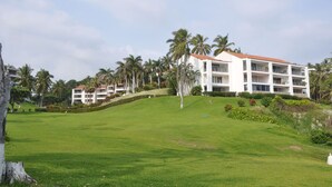 Ein großes, mehrstöckiges Hotel mit weißer Fassade und rotem Dach, umgeben von üppiger Vegetation und Palmen.