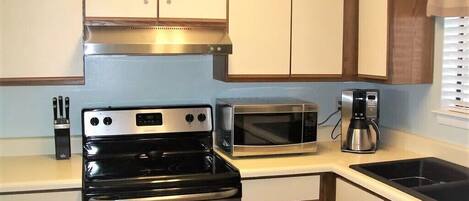 Une cuisine compacte équipée d’une cuisinière, d’un four à micro-ondes et d’une machine à café.