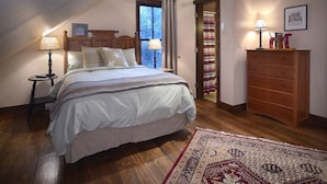 Um quarto com cama, luminárias de cabeceira, cômoda e um tapete estampado.
