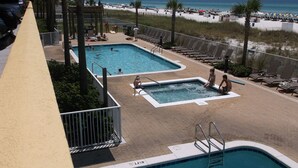 Zona de piscina con dos piscinas, sillas de descanso y vista al mar.