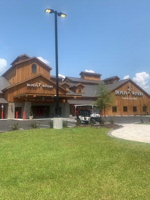 A wooden building with the sign "DUPLIN WINEY" and a golf cart parked in front.