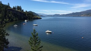 A calm lake with boats, surrounded by forested hills and clear skies. - Cozy house in the shade of pines with Lake and Mountain view (Kelowna)
