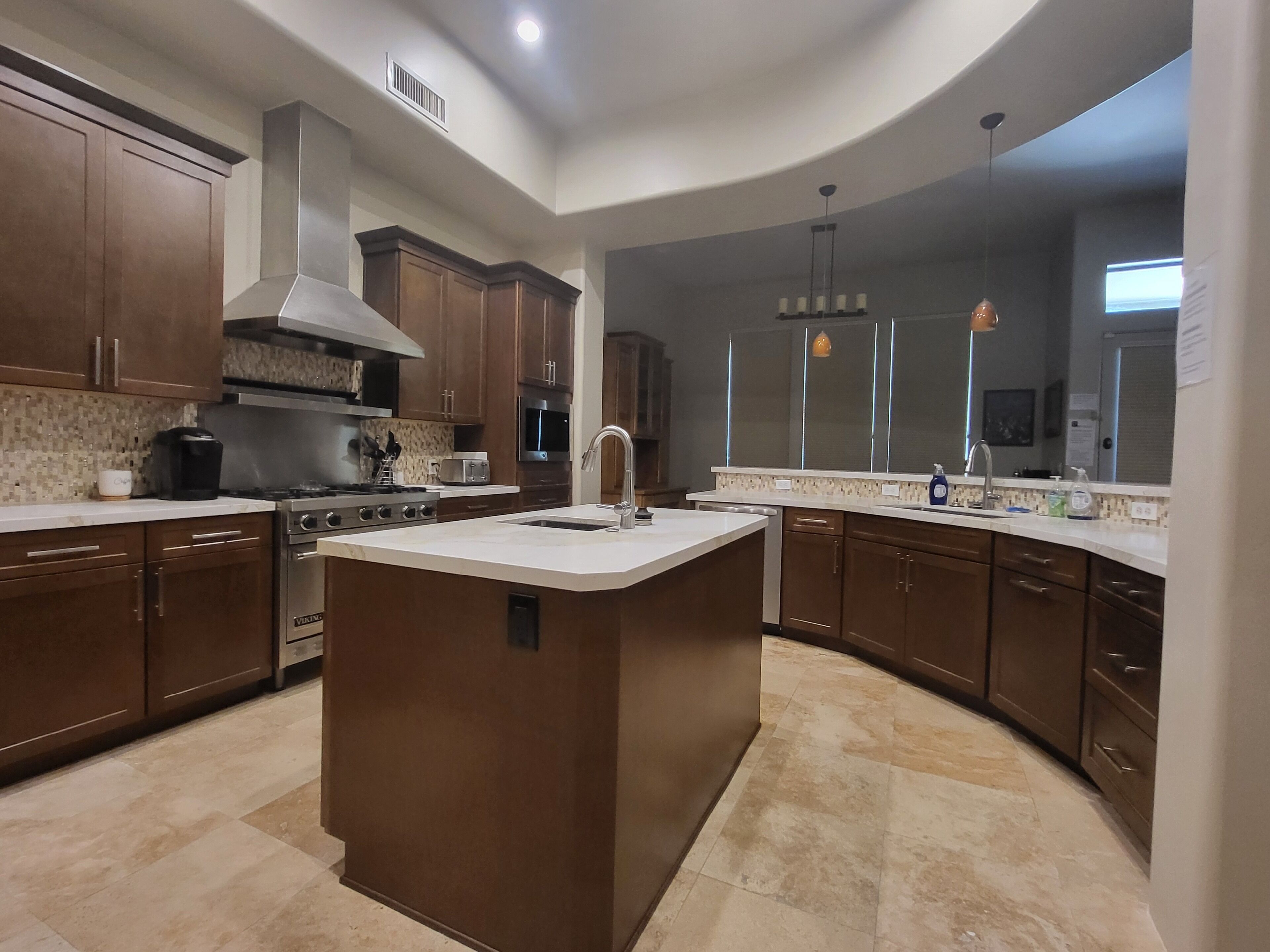 A modern kitchen with a central island, stainless steel appliances, and dark wood cabinets.
