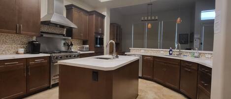A modern kitchen with a central island, stainless steel appliances, and dark wood cabinets.