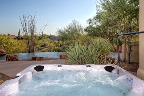 Relax in an outdoor oasis with a hot tub surrounded by lush greenery.