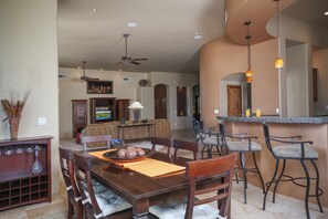 Enjoy meals in this dining area with a large table for four, a bar with stools, and a mounted TV.