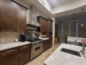 Enjoy cooking in this well-equipped kitchen with an oven, stainless steel range hood, and modern sink.