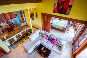 A spacious living area with a sofa, coffee table, and kitchen in the background.