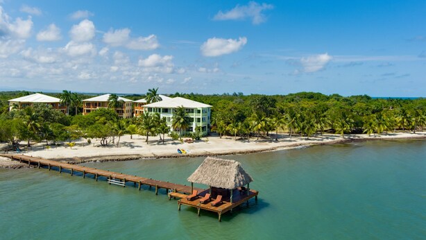 Un resort con bungalows sobre el agua, una playa y un muelle.
