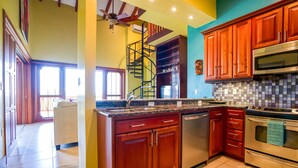 Una cocina con armarios de madera, electrodomésticos de acero inoxidable, una escalera en espiral y un salpicadero de azulejos.
