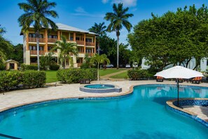 Un hôtel doté d’une piscine, de palmiers et d’une pelouse bien entretenue.