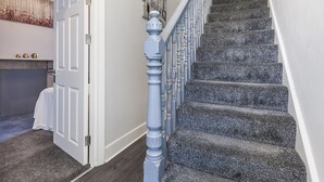 Un escalier avec une rampe bleue et des marches recouvertes de moquette.