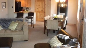 Een woonkamer met een bank, een salontafel en een eethoek met een tafel en stoelen.