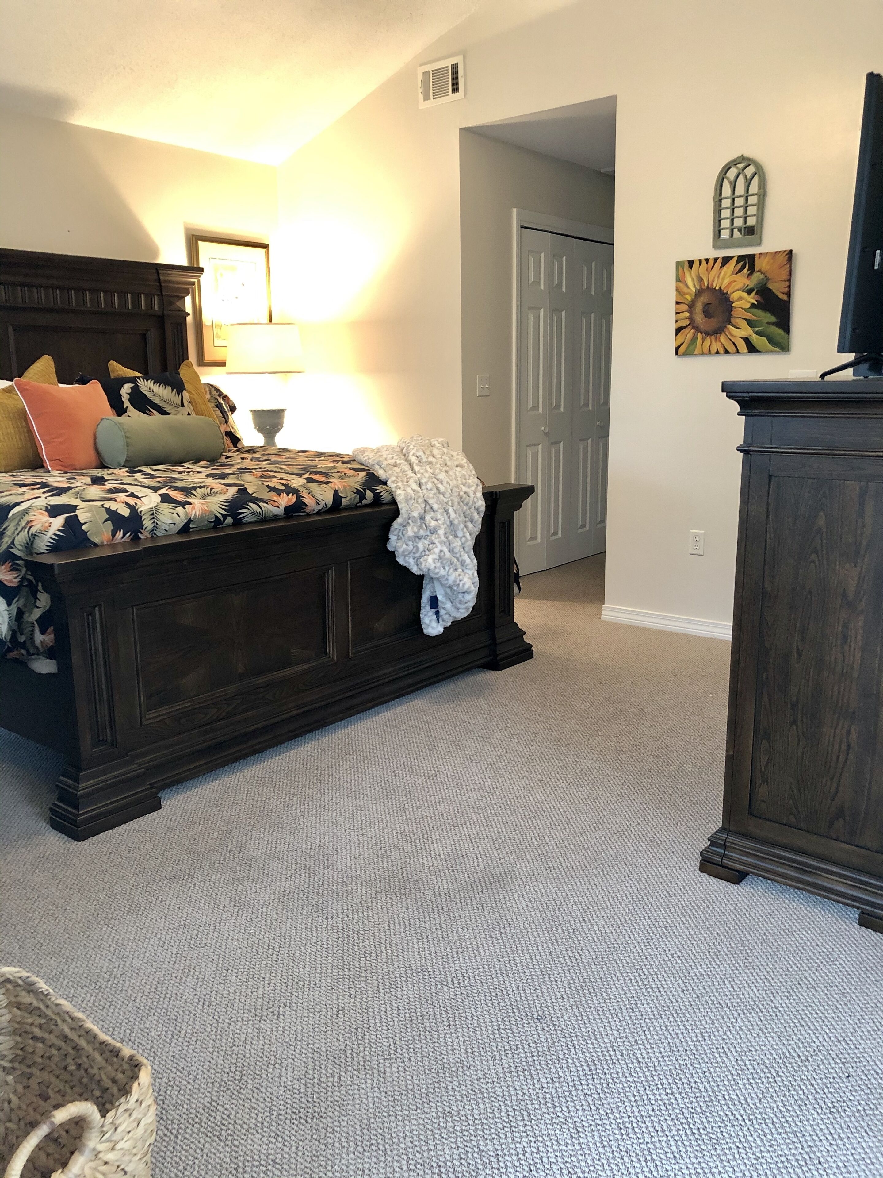 Ein Schlafzimmer mit Bett, Kommode, Lampe und einem Gemälde an der Wand.