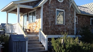 A two-story wooden building with a covered porch and a staircase leading to the entrance.