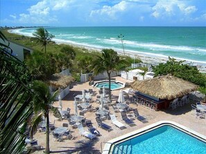 A resort with a pool, lounge chairs, and a view of the ocean.