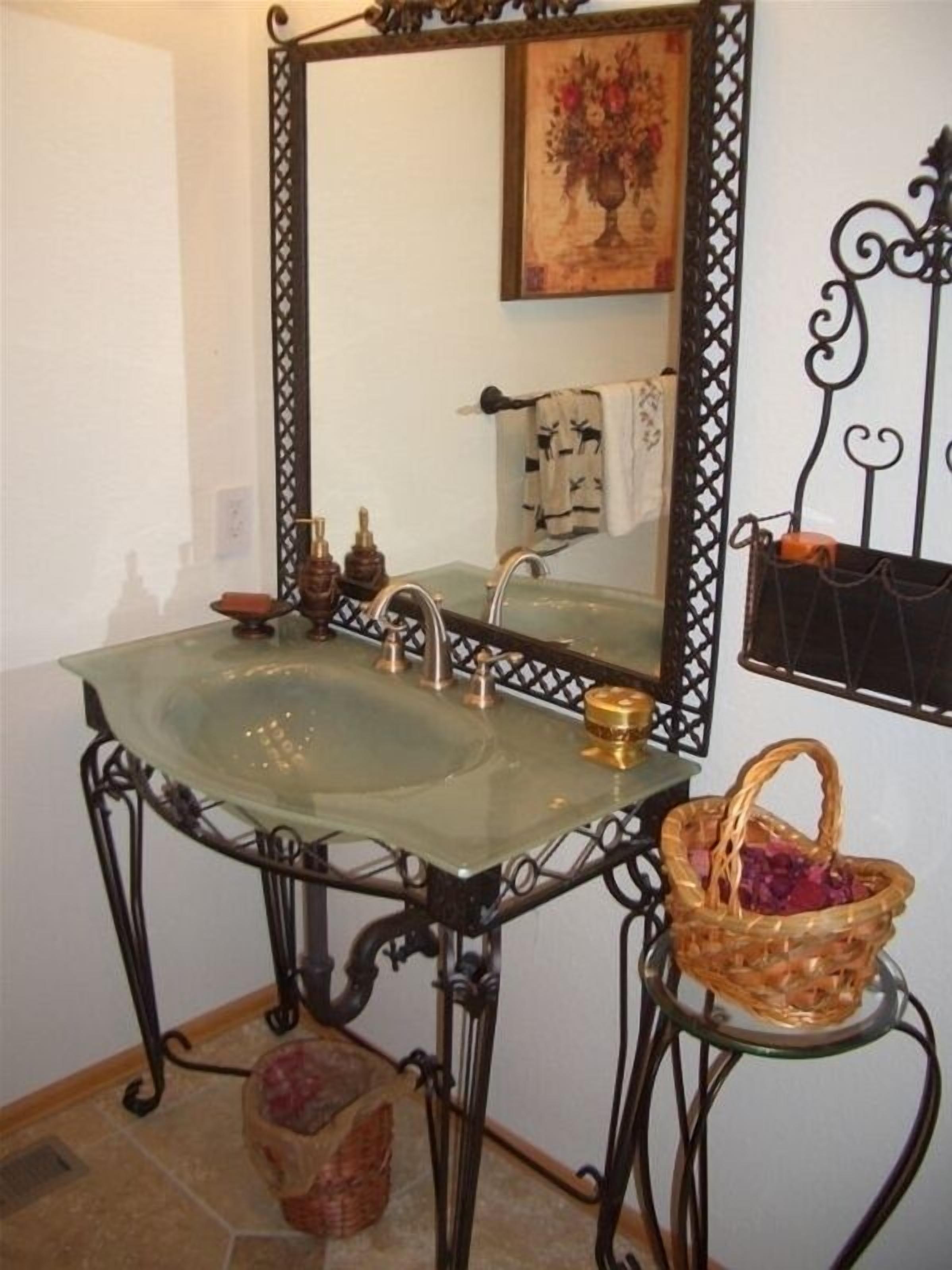 Casa de banho com lavatório de vidro, espelho e cesto decorativo.
